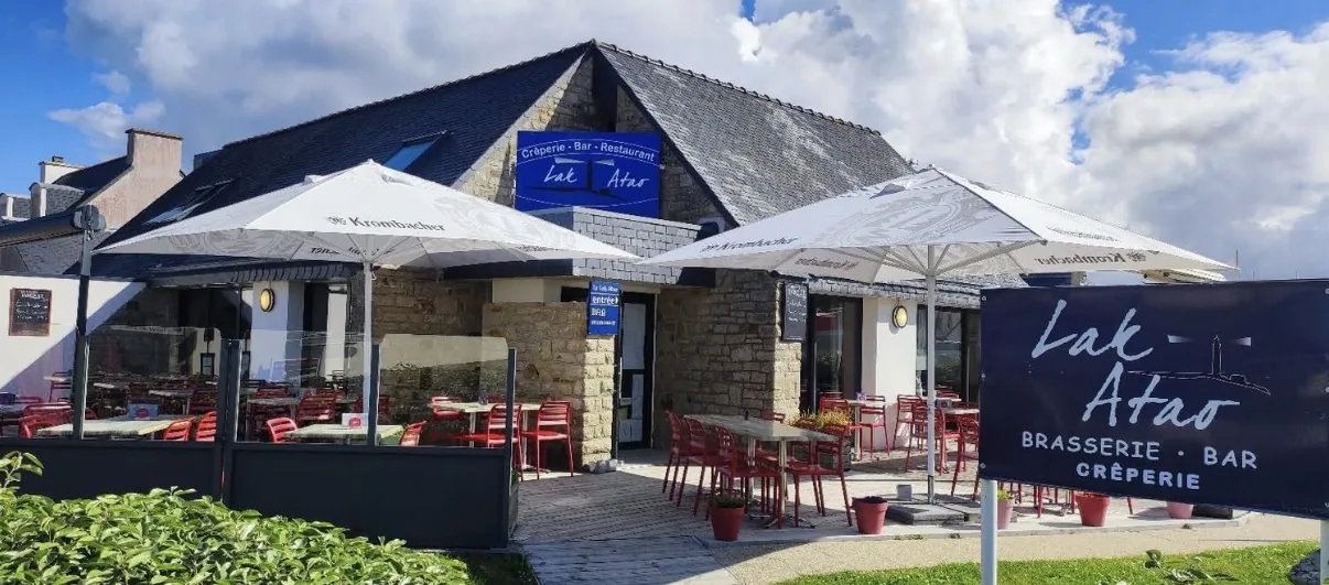 La maison Lak Atao : façade en pierre, toit d'ardoise, enseigne et terrasse aux chaises rouges